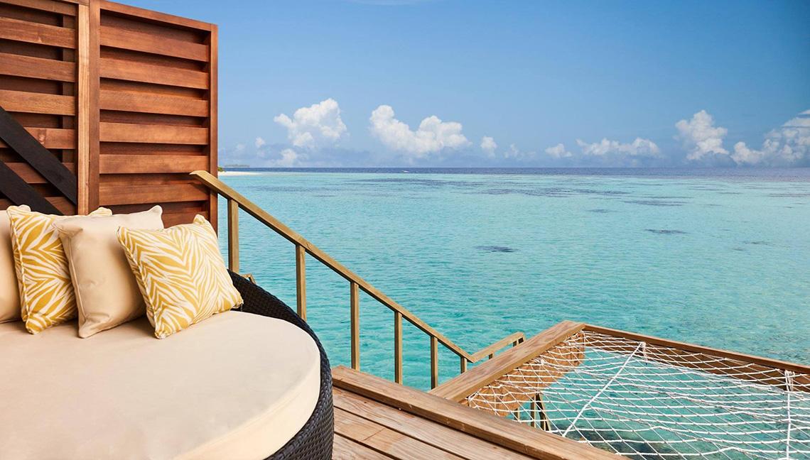 Terrasse des Amari Havodda Maldives mit Sofa und Hängematte mit Blick auf das Meer