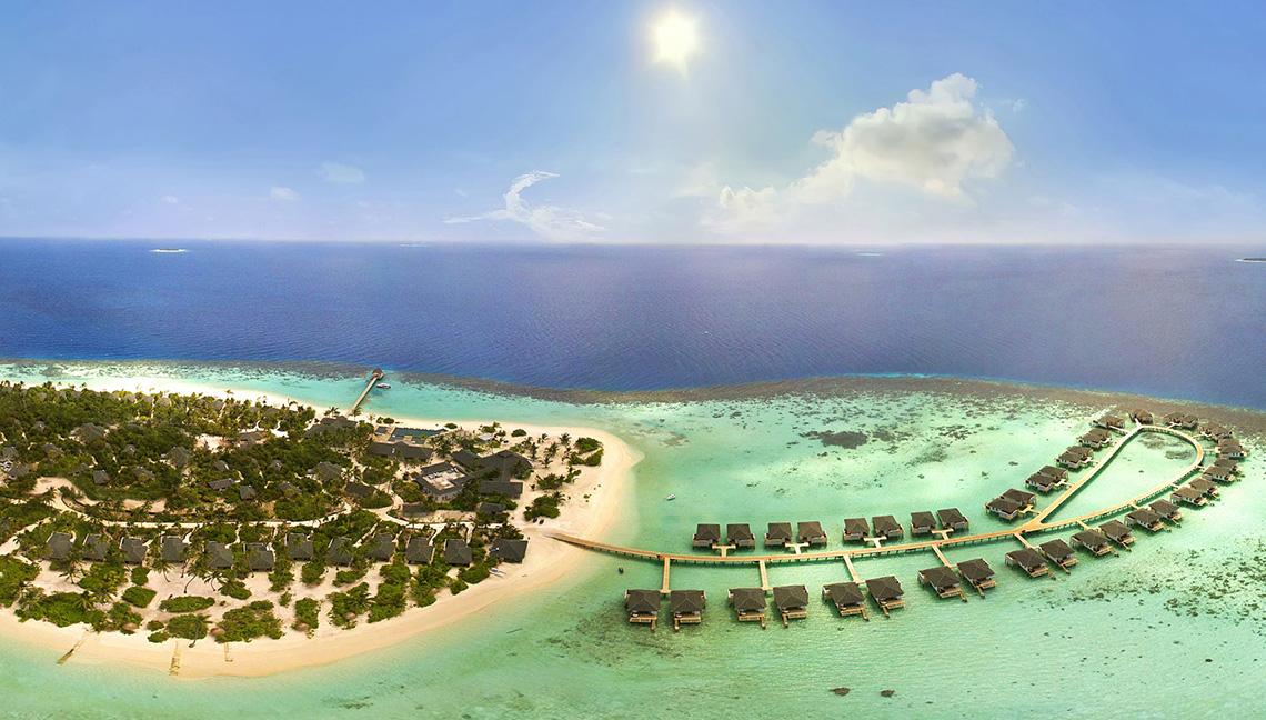 Luftaufnahme des Amari Havodda Maldives Resorts mit Wasserbungalows und blauem Ozean.