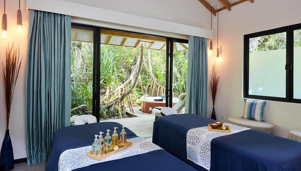 Spa-Behandlungsraum im Amari Havodda Maldives mit Blick auf einen Whirlpool im Freien.