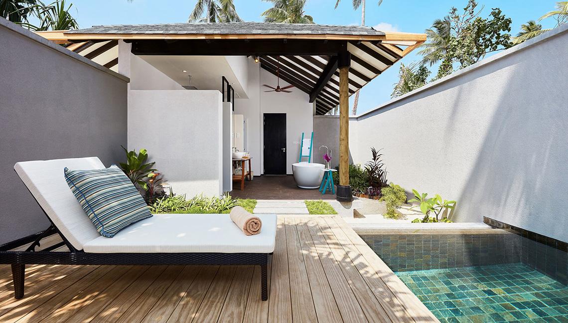 Außenbereich des Amari Havodda Maldives mit Liege, Pool und traditionellem Dach.