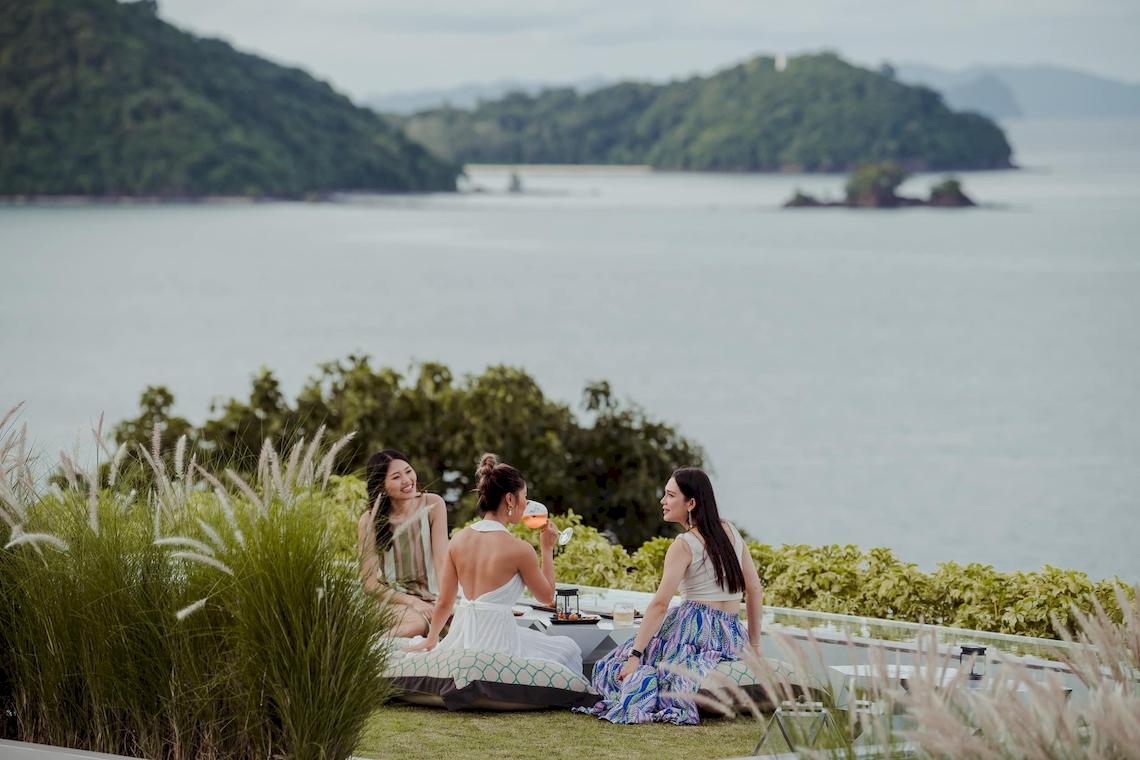 Drei Frauen sitzen auf einer Terrasse mit Blick auf das Meer im Amatara Welleisure Resort.