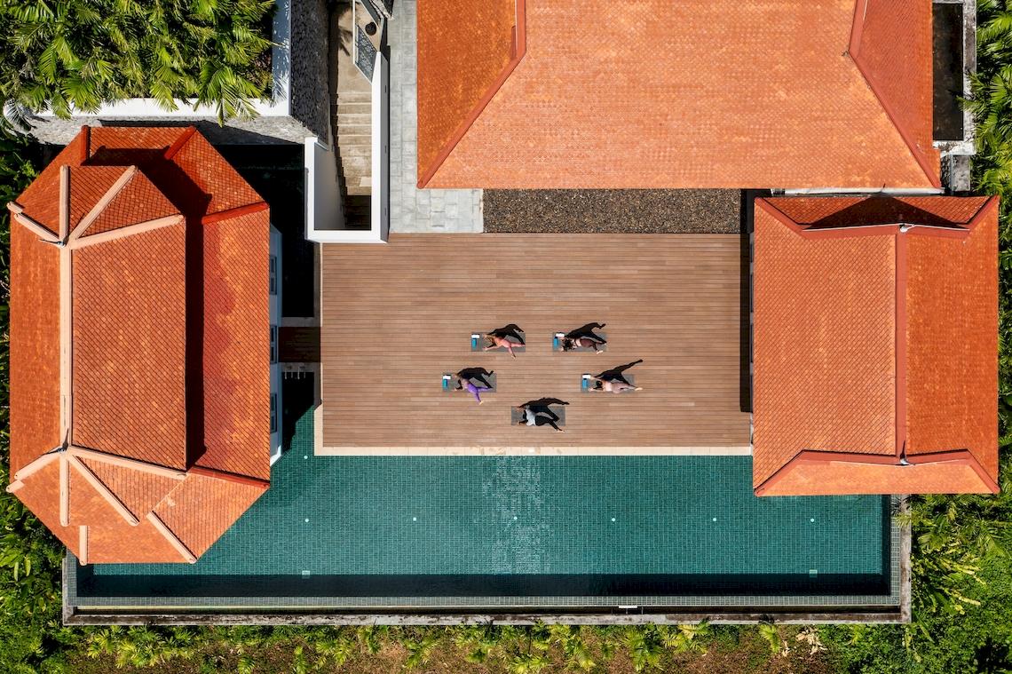 Aerial view of Amatara Welleisure Resort with people doing yoga on the terrace.