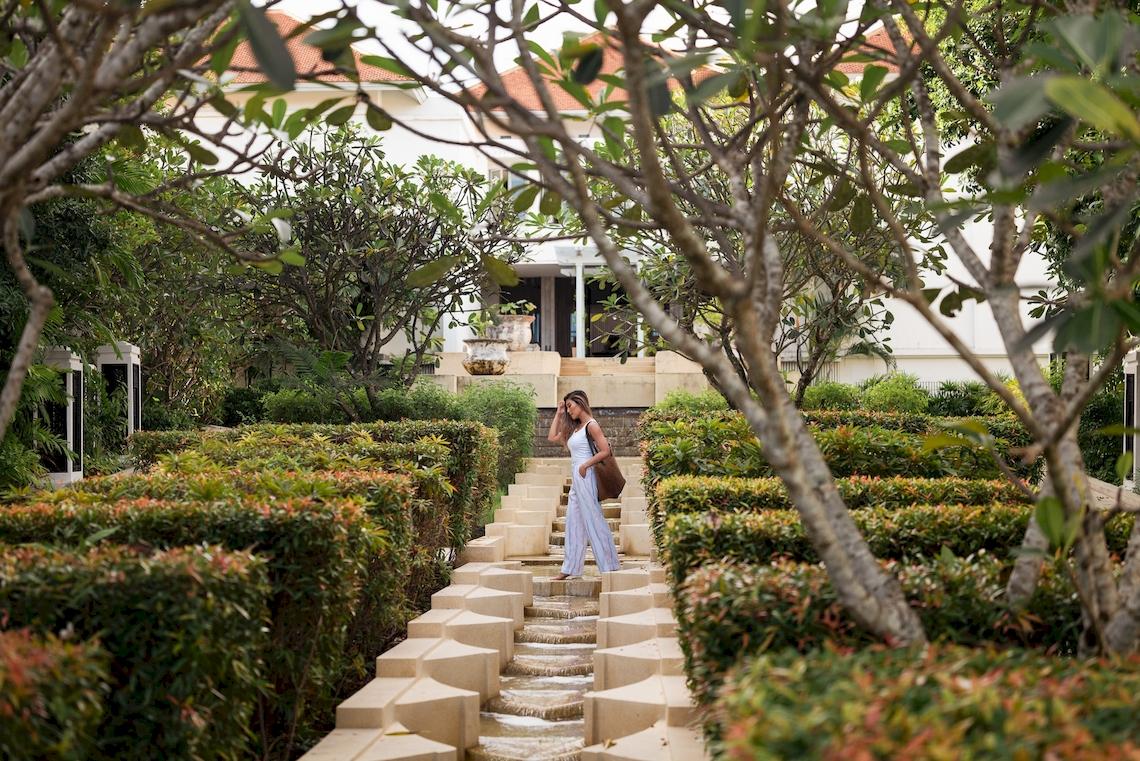 Frau spaziert durch den Garten des Amatara Welleisure Resort