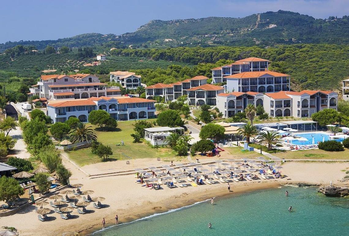 Luftaufnahme des Bay Hotel & Suites mit Strand, Pool und grüner Umgebung.