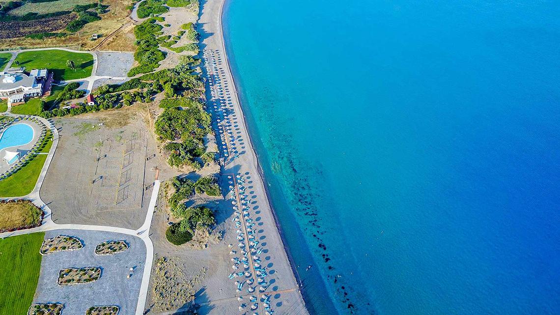 Luftaufnahme des Club Plimmiri Hotels, Strand mit Sonnenliegen und blauem Meer.