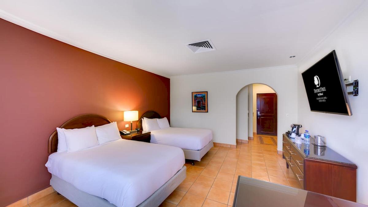 Doppelzimmer im DoubleTree by Hilton Hotel Cariari San Jose mit zwei Betten, Nachttischen und Fernseher.