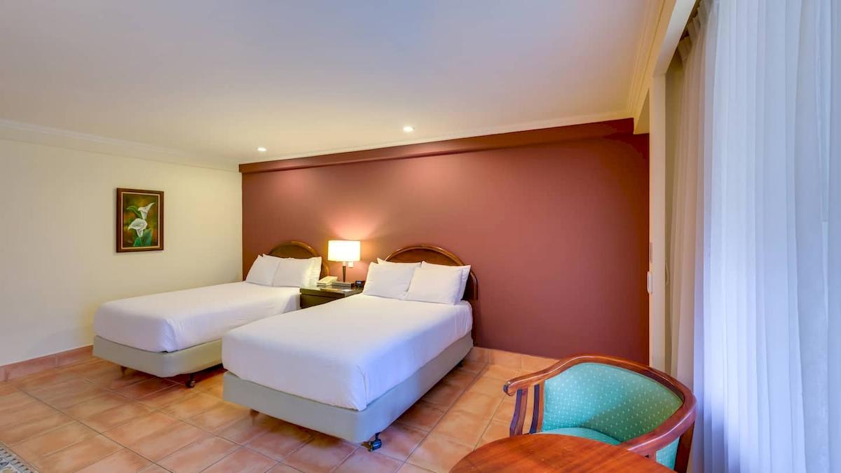 Doppelzimmer im DoubleTree by Hilton Hotel Cariari San Jose mit zwei Betten, Lampen und einem Tisch.