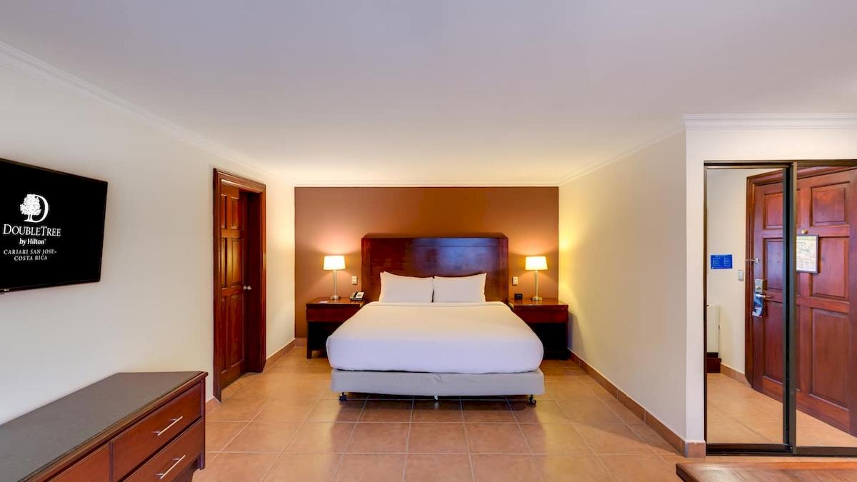 Doppelzimmer im DoubleTree by Hilton Hotel Cariari San Jose mit Bett, Lampen und Fernseher.