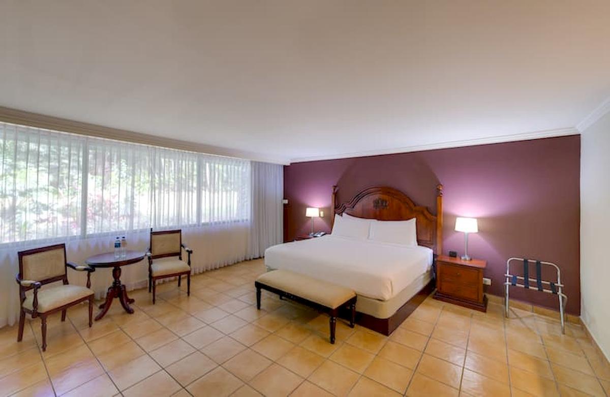 Doppelzimmer im DoubleTree by Hilton Hotel Cariari San Jose mit Bett, Tisch, Stühlen und Nachttischen.