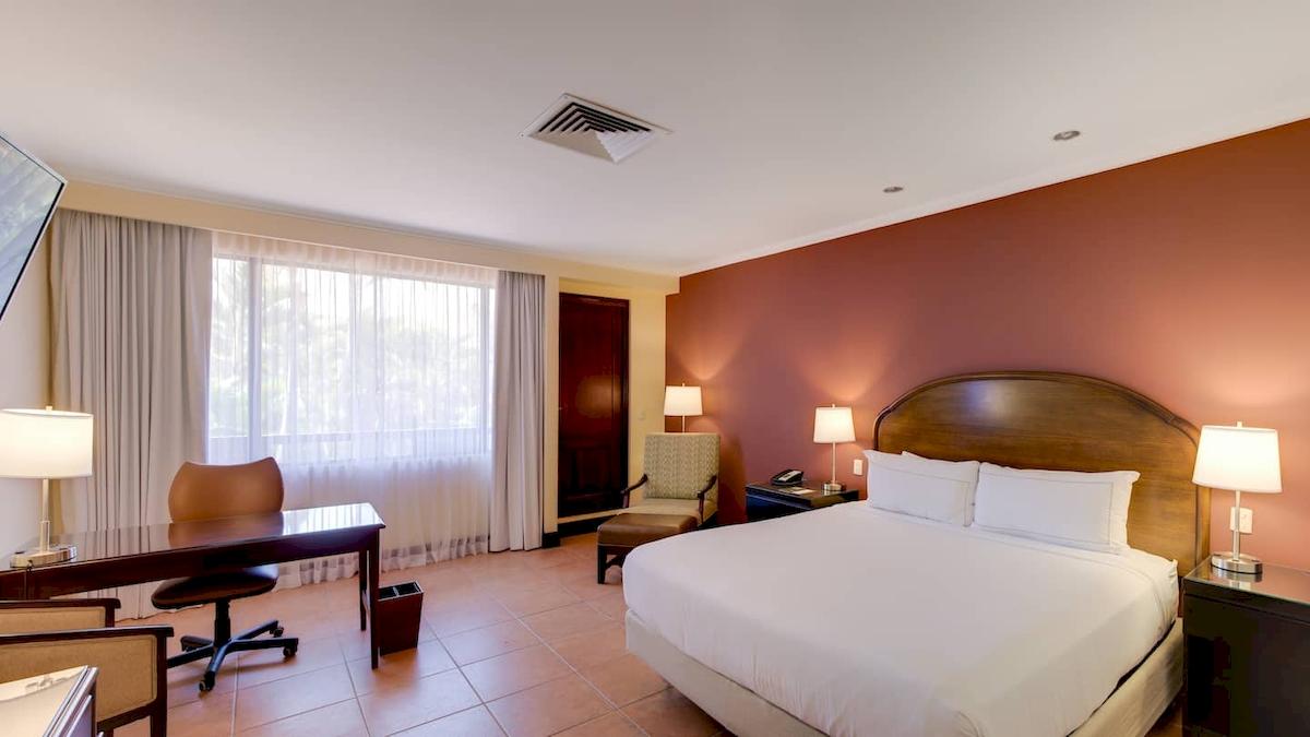 Doppelzimmer im DoubleTree by Hilton Hotel Cariari San Jose mit Bett, Schreibtisch und Fenstern.