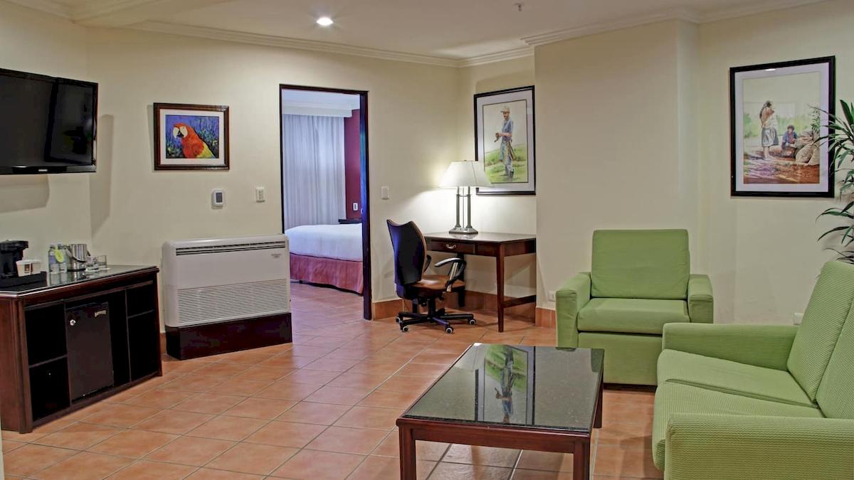 Doppelzimmer im DoubleTree by Hilton Hotel Cariari San Jose mit Wohnzimmer, Schlafzimmer, Schreibtisch und Möbeln.