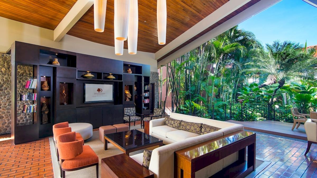 Lobby des DoubleTree by Hilton Hotel Cariari San Jose mit Inneneinrichtung und Ausblick auf Pflanzen.