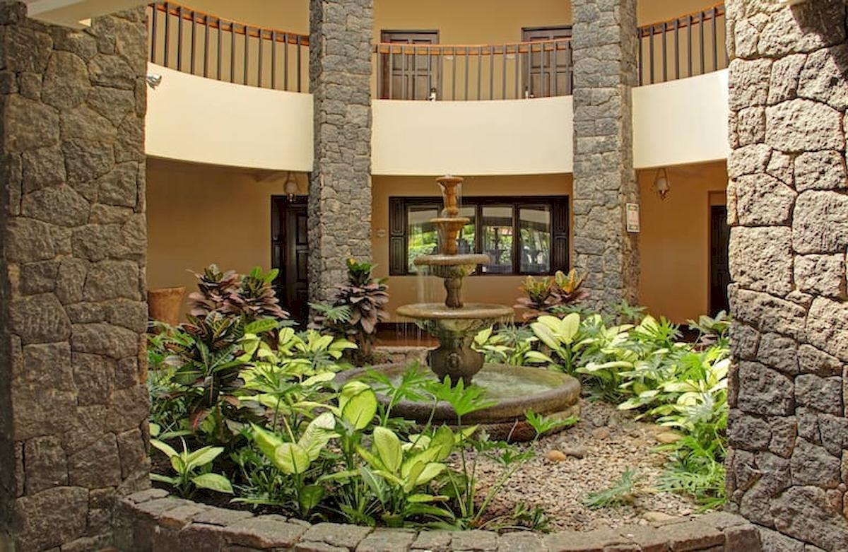 Gartenbereich des DoubleTree by Hilton Hotel Cariari mit einem zentralen Wasserbrunnen und umliegenden Pflanzen.