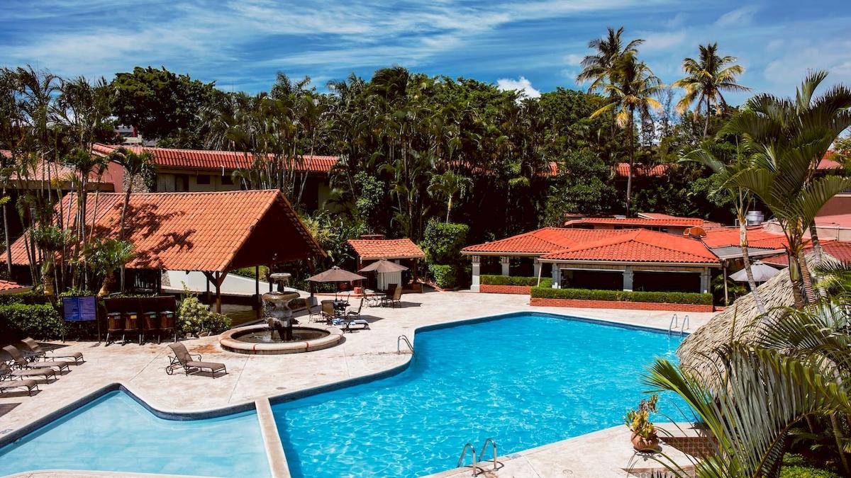 Außenbereich des DoubleTree by Hilton Hotel Cariari San Jose mit Swimmingpool und Sonnenliegen.