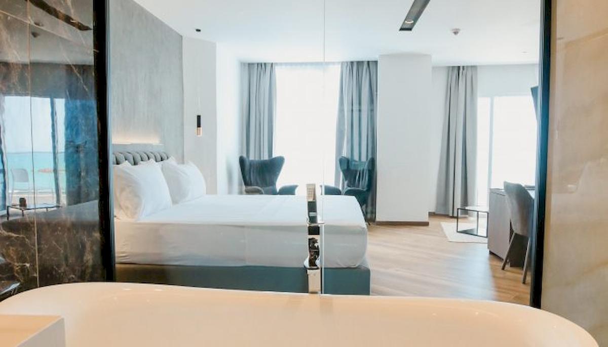 Schlafzimmer im Klajdi Resort & SPA Hotel mit Doppelbett, Badewanne und Meerblick.