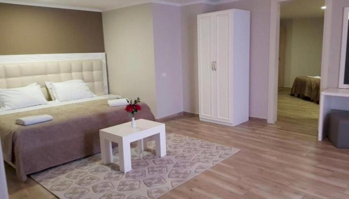 Schlafzimmer im Klajdi Resort & SPA mit Bett, Tisch, Blumen und Schrank.
