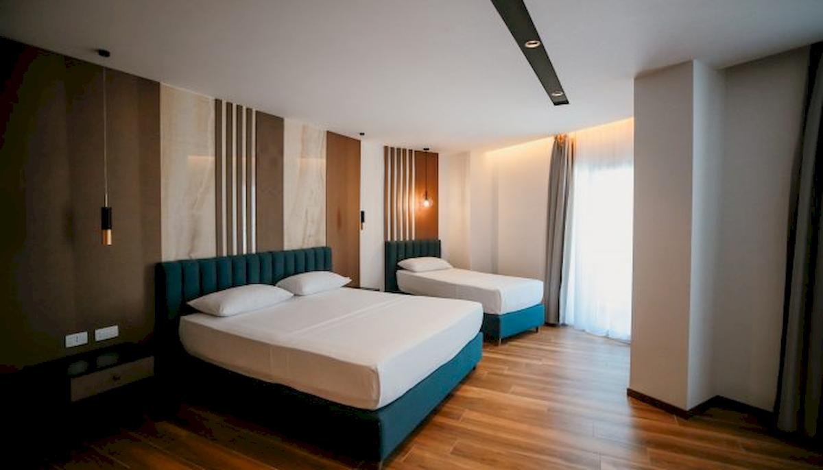 Zwei Betten im Schlafzimmer des Klajdi Resort & SPA, beide mit weißen Laken und Kissen, neben einem Nachttisch.