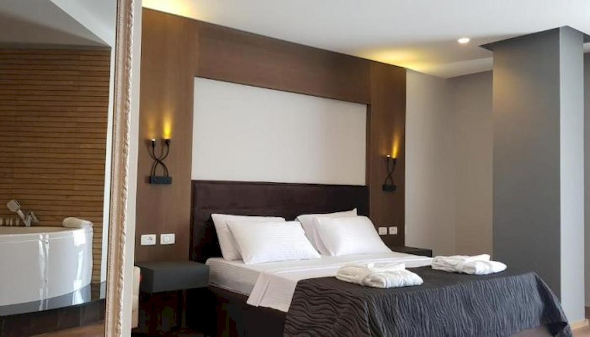 Schlafzimmer im Klajdi Resort & SPA mit einem großen Bett, weißen Kissen und einem Badewanne.