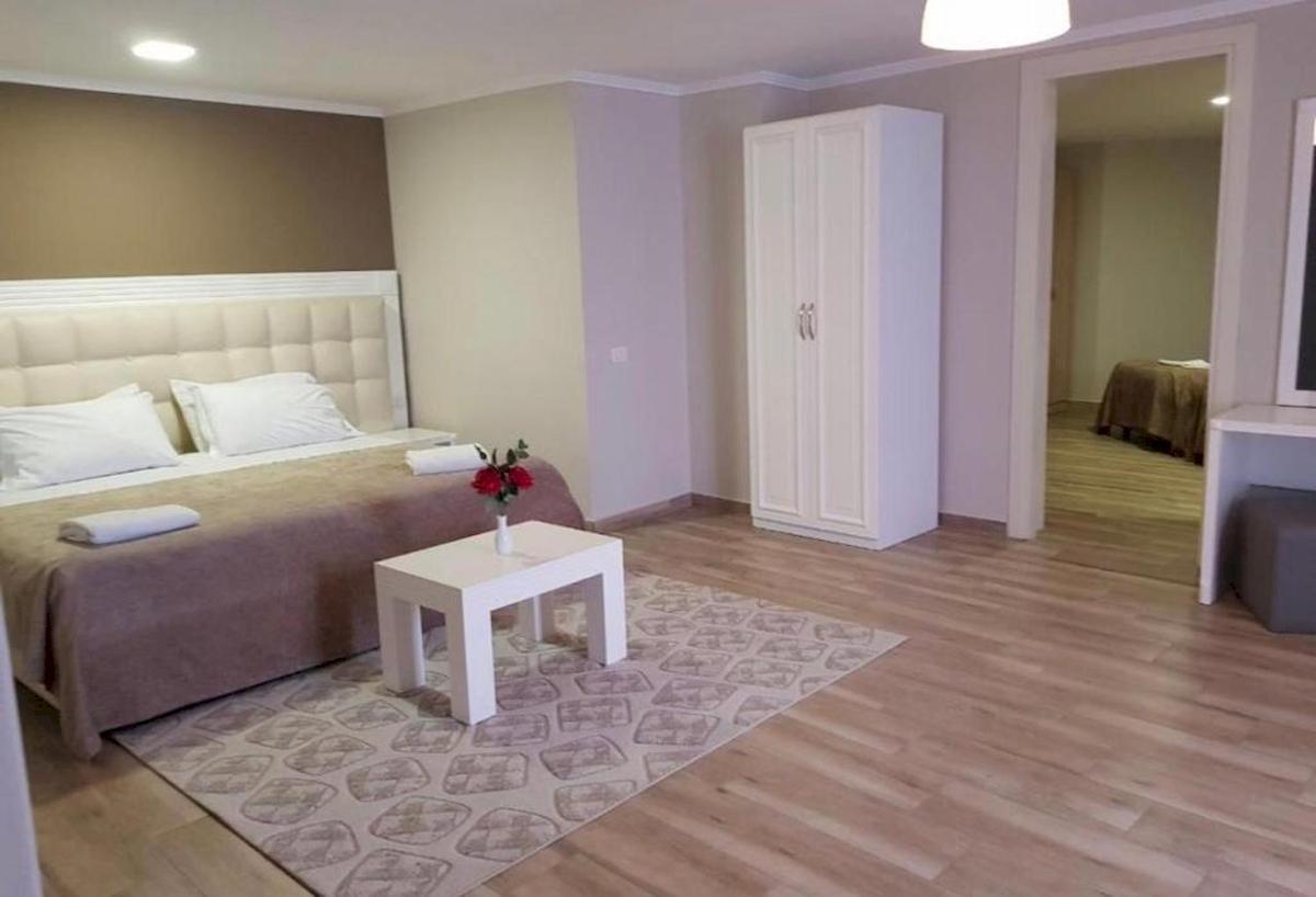 Schlafzimmer im Klajdi Resort & SPA mit einem Bett, Tisch, Vase mit Blumen und Schrank.