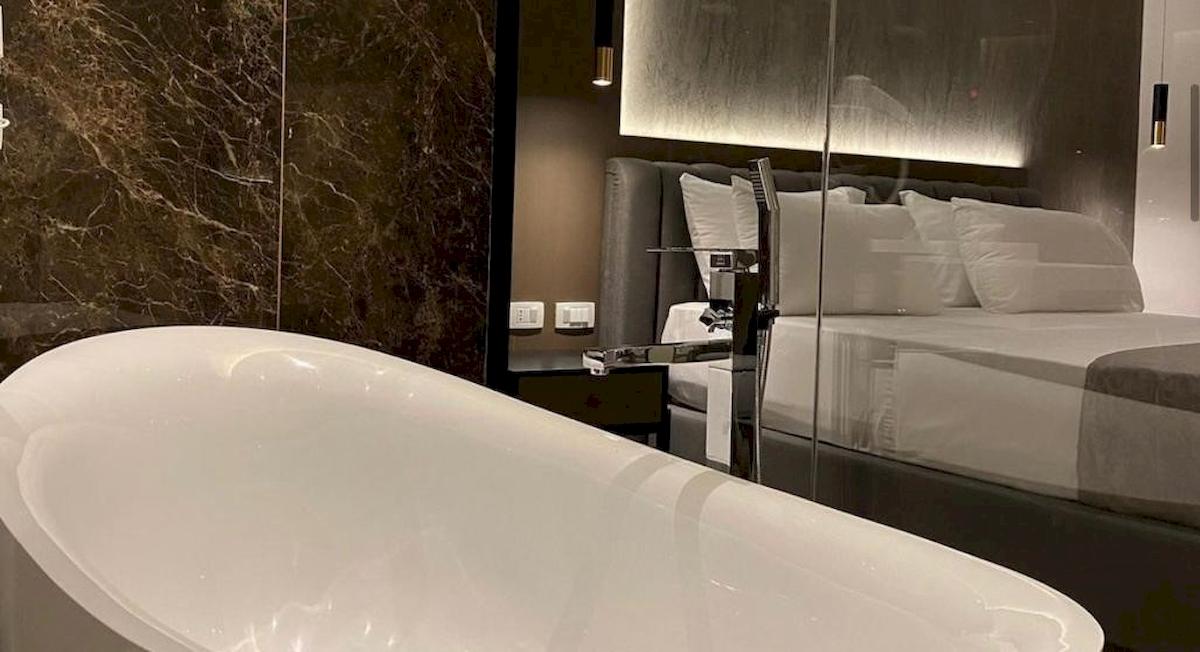 Schlafzimmer im Klajdi Resort & SPA mit Badewanne, Bett und Marmorwand