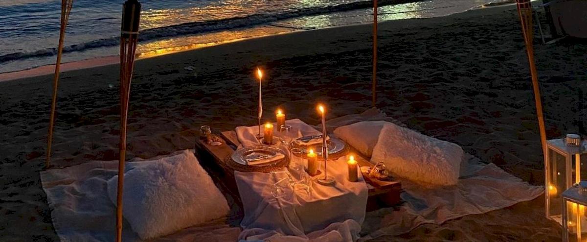 Dinner-Setup am Strand des Klajdi Resort & SPA mit Kerzen und Tischdecken.