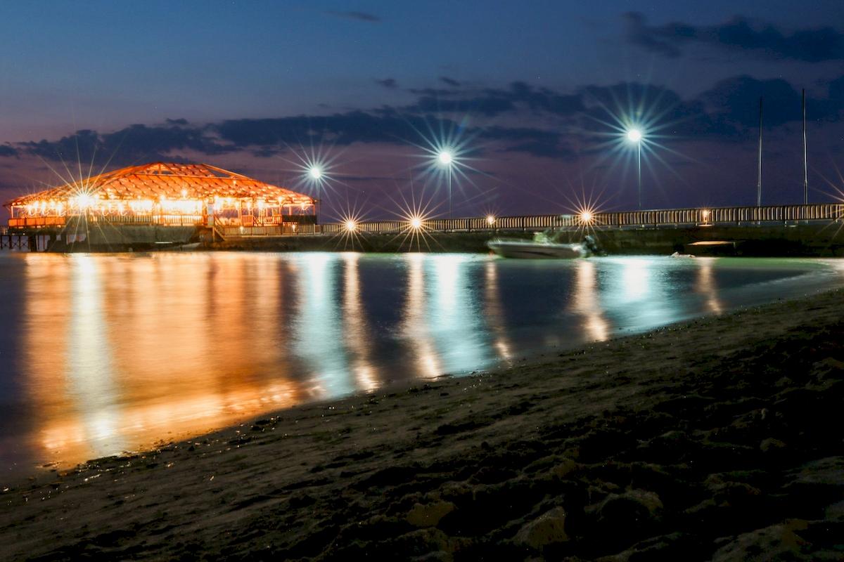 Das Klajdi Resort & SPA bei Nacht, mit Beleuchtung und Wasserreflexion.