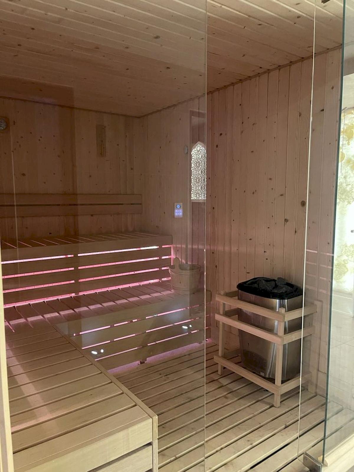 Innenansicht der Sauna im Klajdi Resort mit Holzwänden und Bänken, die mit roten Lichtern beleuchtet sind.