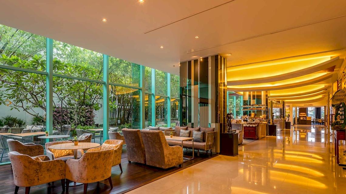 Lobby des Chatrium Hotel Riverside Bangkok mit großen Glaswänden und modernen Möbeln.