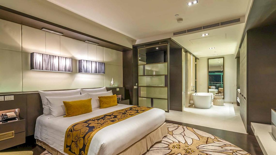 Schlafzimmer im Chatrium Hotel Riverside Bangkok mit Doppelbett, gelben Kissen und moderner Einrichtung.