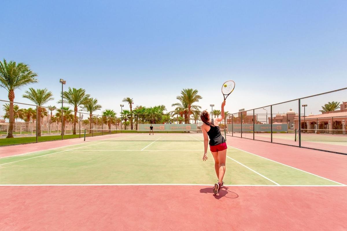 Tennisplatz im Pickalbatros Aqua Vista Resort mit einer Spielerin, die einen Ball schlägt.