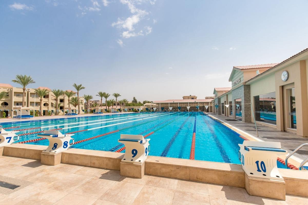 Außenpool des Pickalbatros Aqua Vista Resorts mit nummerierten Bahnen und Gebäuden im Hintergrund.