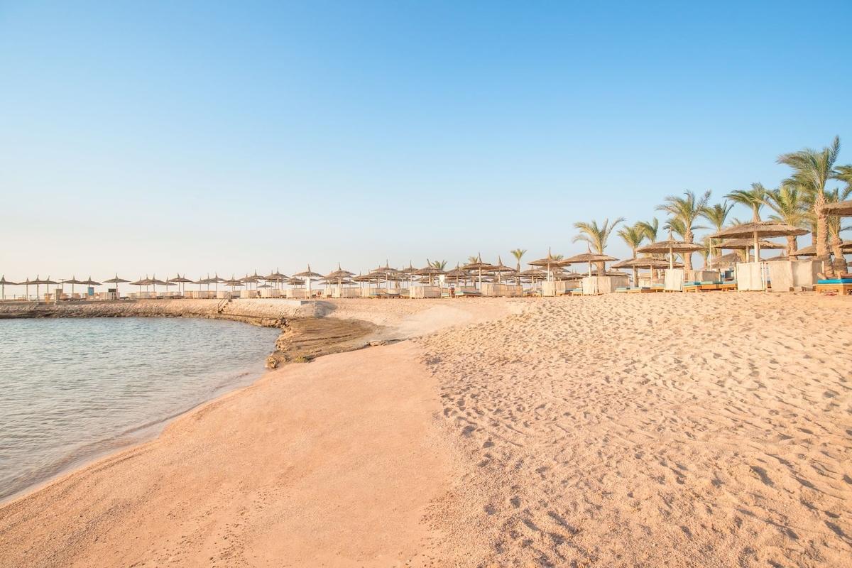Strand des Pickalbatros Aqua Vista Resorts mit vielen Sonnenschirmen und Palmen