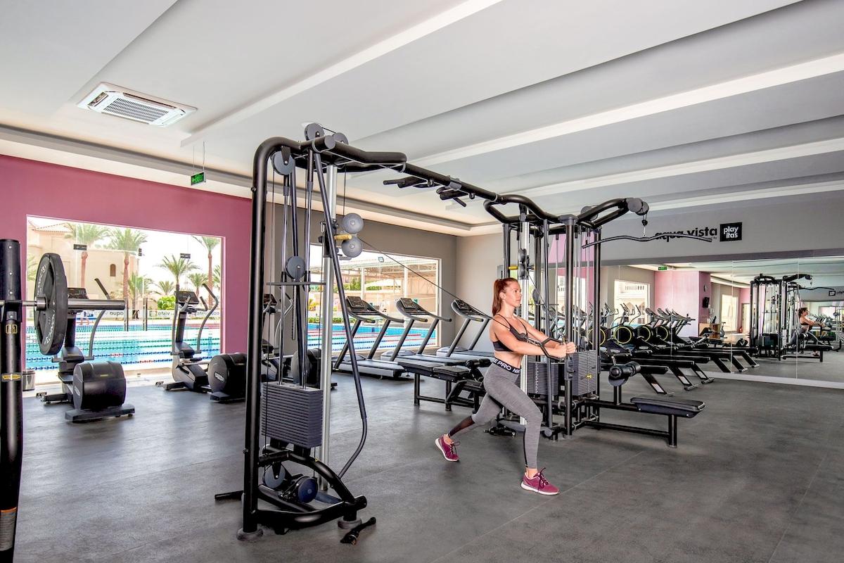 Fitness-Center im Pickalbatros Aqua Vista Resort mit einer Frau, die an einem Kraftgerät trainiert.