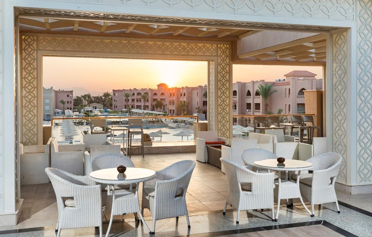 Terrasse des Pickalbatros Aqua Vista Resorts mit Blick auf den Sonnenuntergang und den Pool.