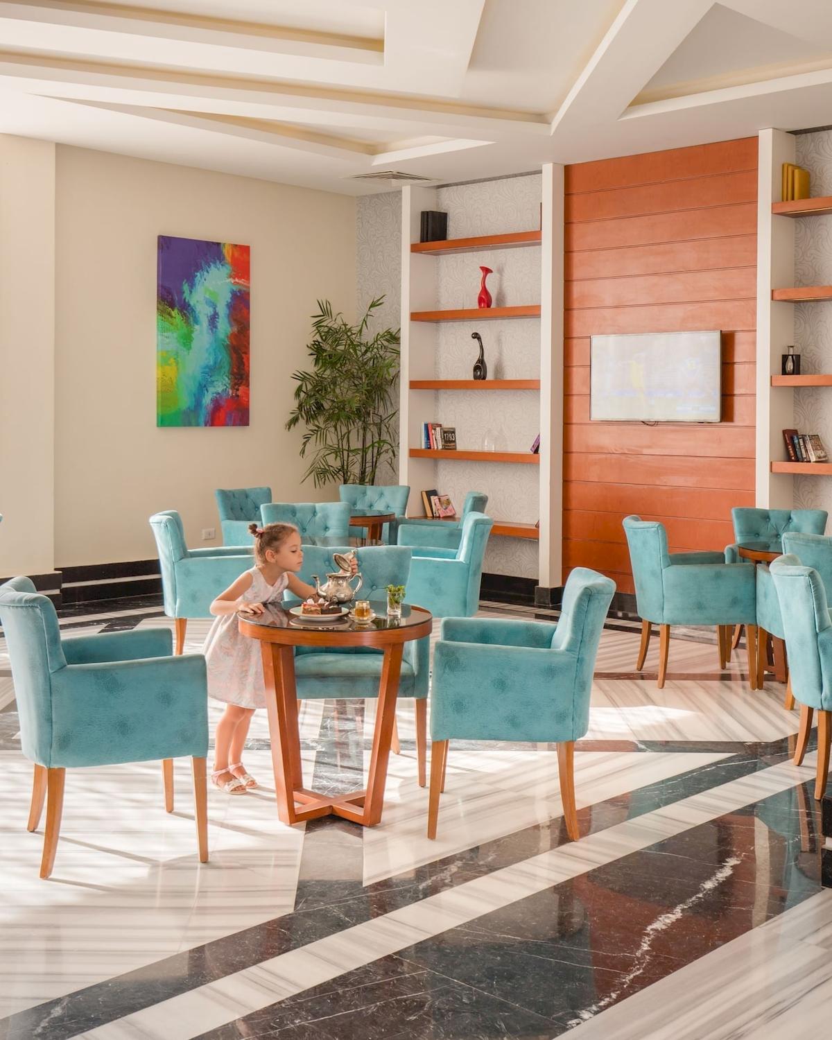 Ein Mädchen sitzt in einem blauen Stuhl in der Lobby des Pickalbatros Aqua Vista Resort Hotels.