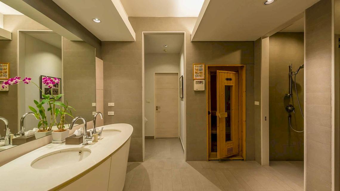 Das Badezimmer im Chatrium Hotel Riverside Bangkok mit zwei Waschbecken, Spiegel und einem offenen Saunaraum.