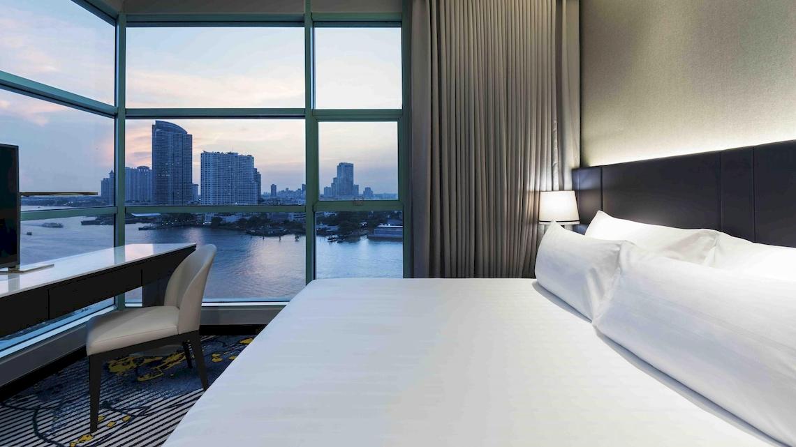 Zimmer im Chatrium Hotel Riverside Bangkok mit Blick auf die Skyline und den Fluss.