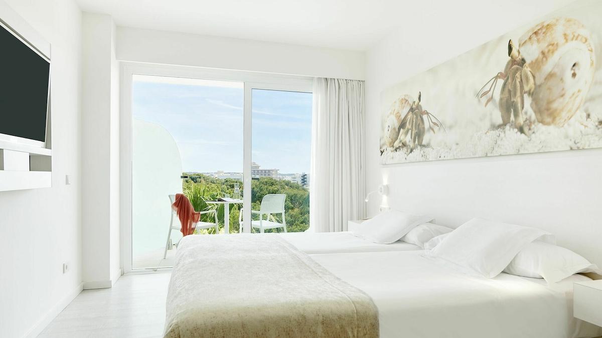 Zimmer mit zwei Betten und Aussicht auf einen Garten und eine Stadt