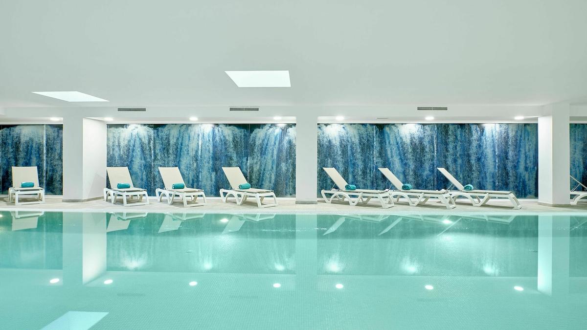 Innenpool im Iberostar Cristina Hotel mit weißen Liegen und blauen Wänden