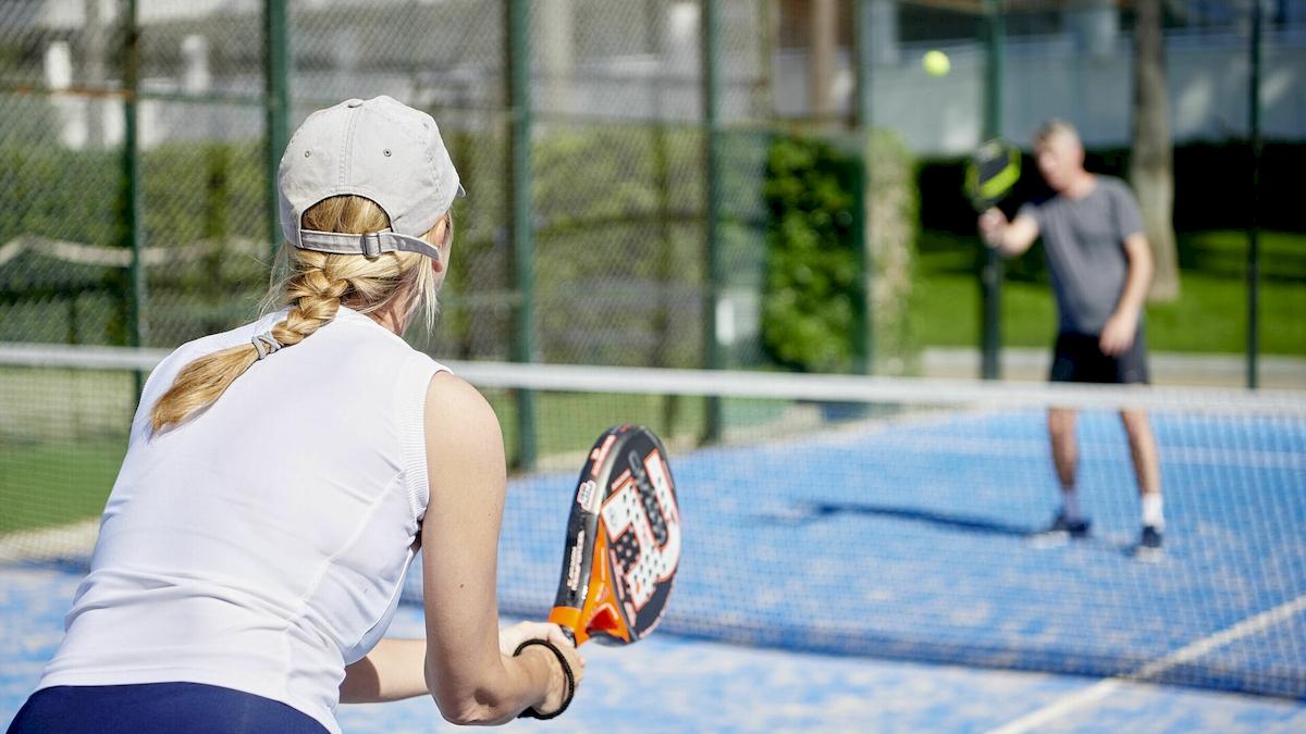 Zwei Personen spielen Tennis auf einem blauen Tennisplatz im Freien.