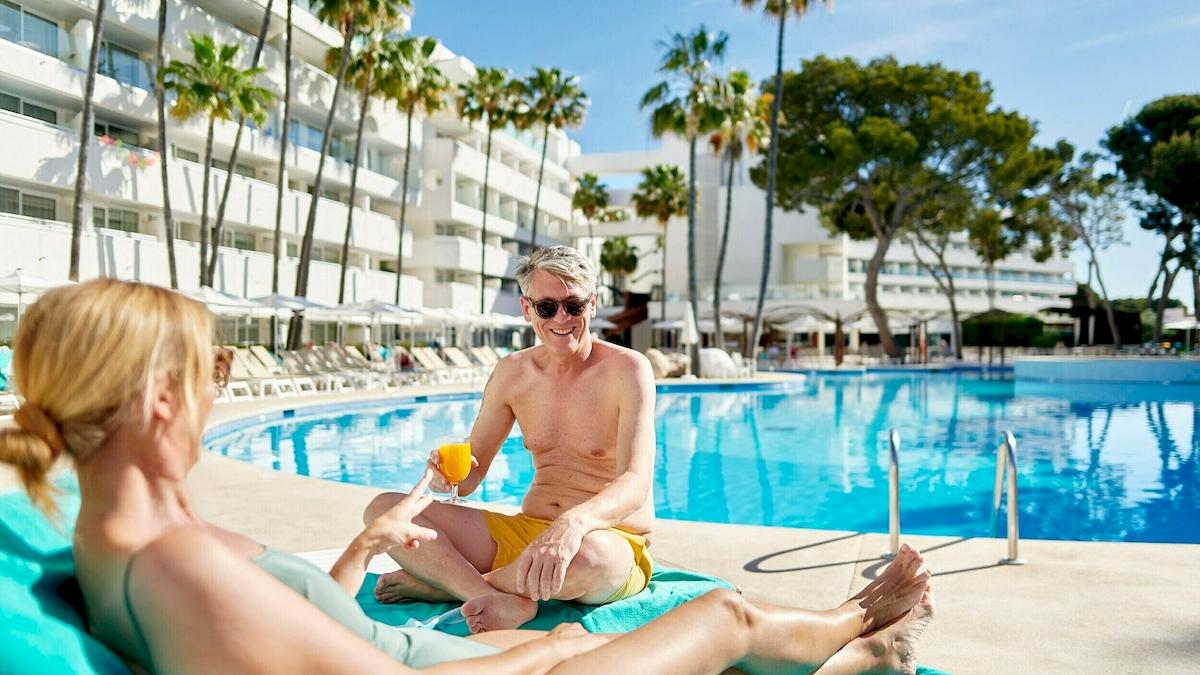 Paar am Pool im Iberostar Cristina Hotel, das auf einem Liegestuhl sitzt