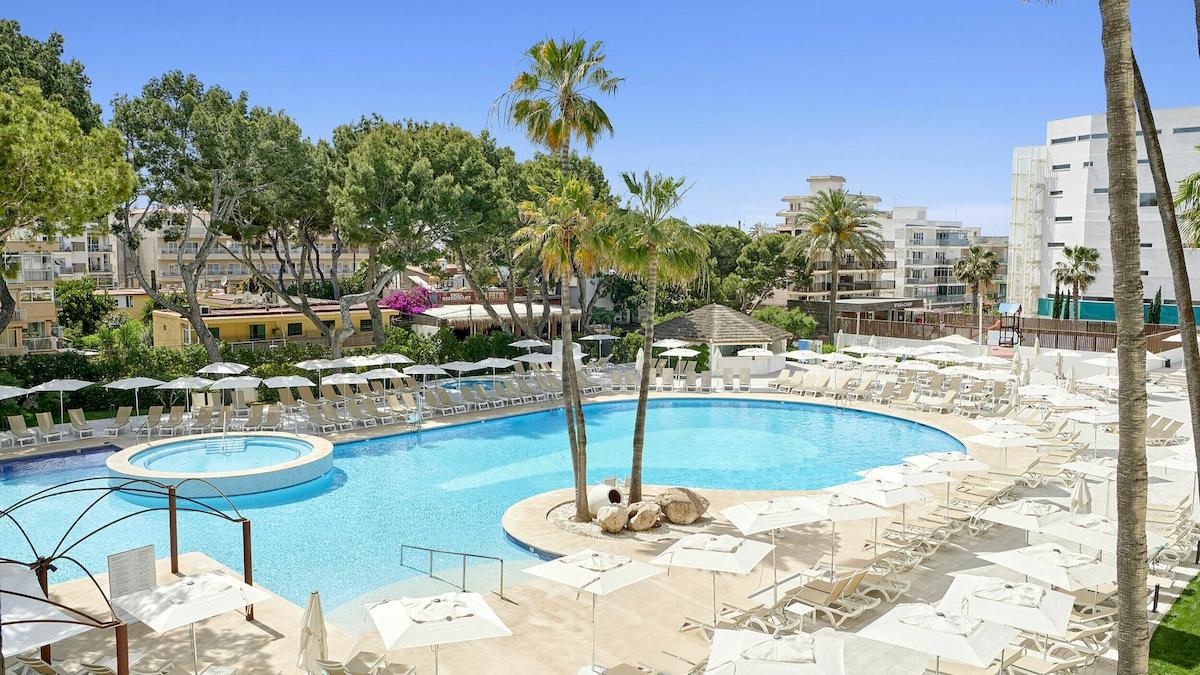 Außenbereich des Iberostar Cristina Hotels mit Swimmingpool und Sonnenliegen