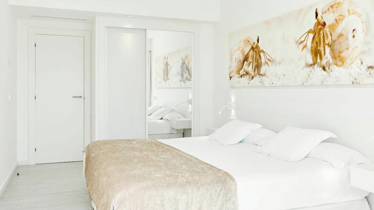 Weißes Schlafzimmer mit modernen Möbeln und Kunstwerken in einem Hotelzimmer.