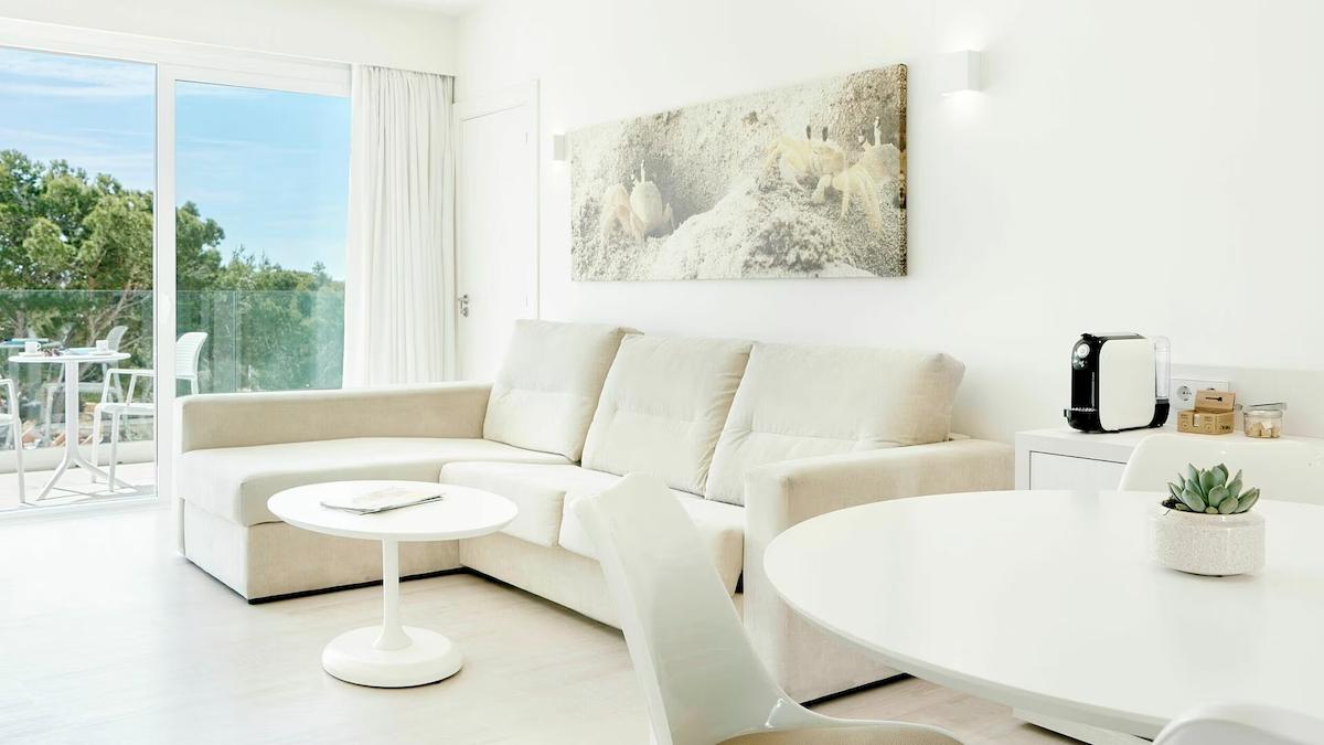 Wohnzimmer im Iberostar Cristina Hotel mit Sofa, Tisch und Aussicht auf den Garten.