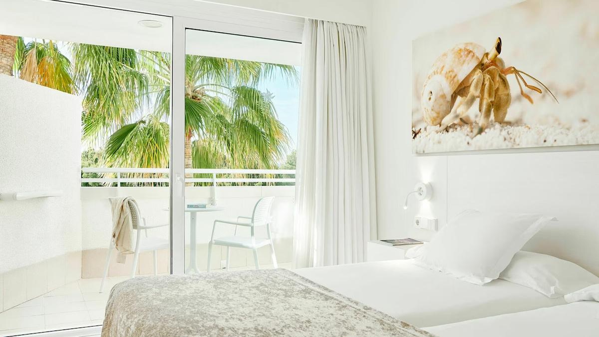 Zimmer im Iberostar Cristina Hotel mit Terrasse und Ausblick auf Palmen und Meer.