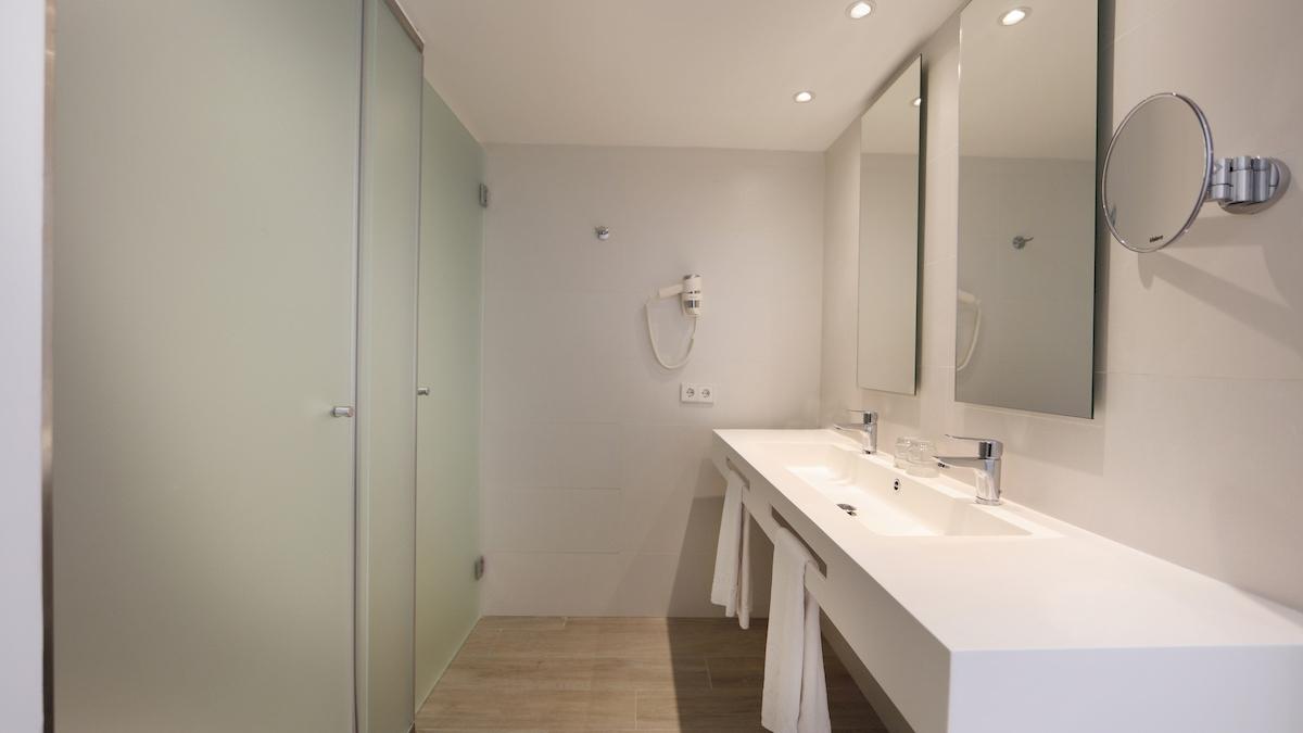 Badezimmer im Iberostar Playa de Muro mit Dusche, Spiegeln und Waschbecken.