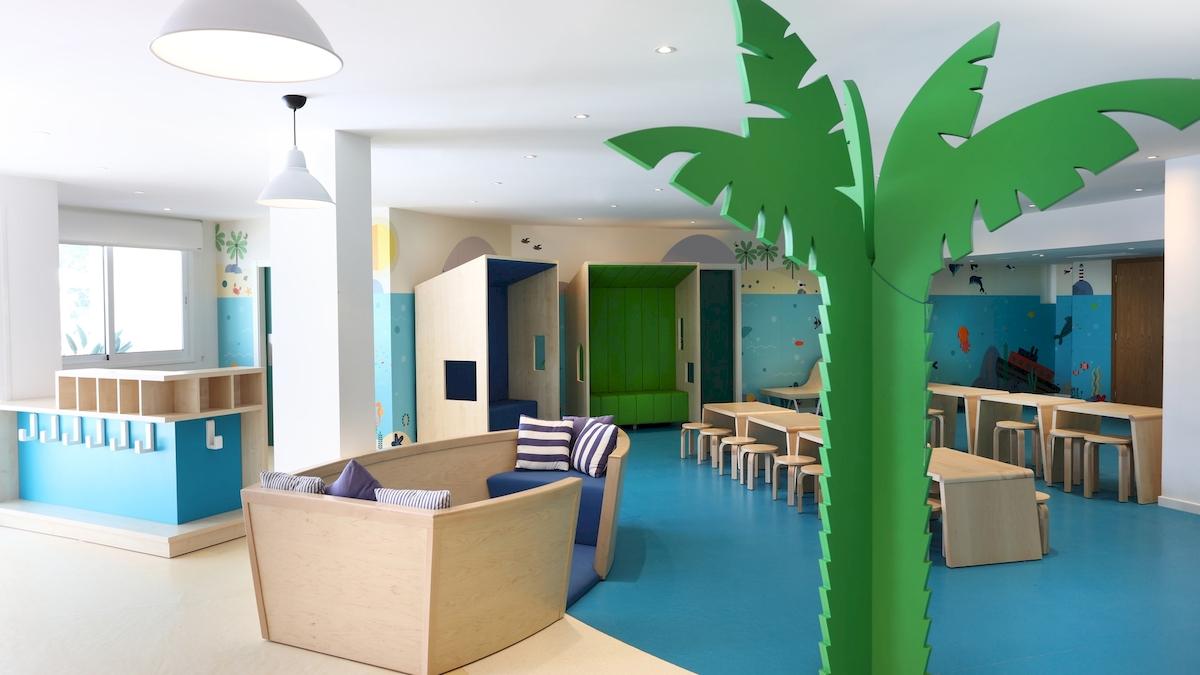 Kinderbereich im Iberostar Playa de Muro Hotel mit blauem Boden, bunten Wänden und Sitzmöbeln.