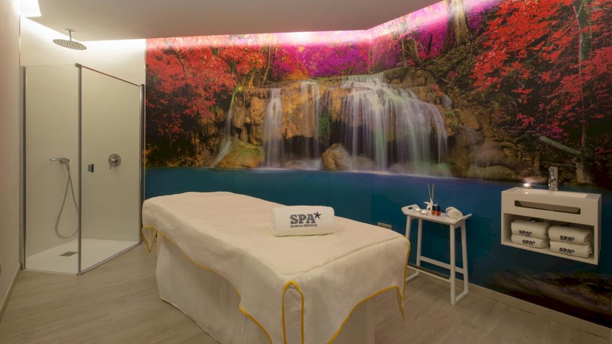 SPA-Behandlungsraum im Iberostar Playa de Muro Hotel mit Wasserfall-Wandbild und Behandlungstisch.