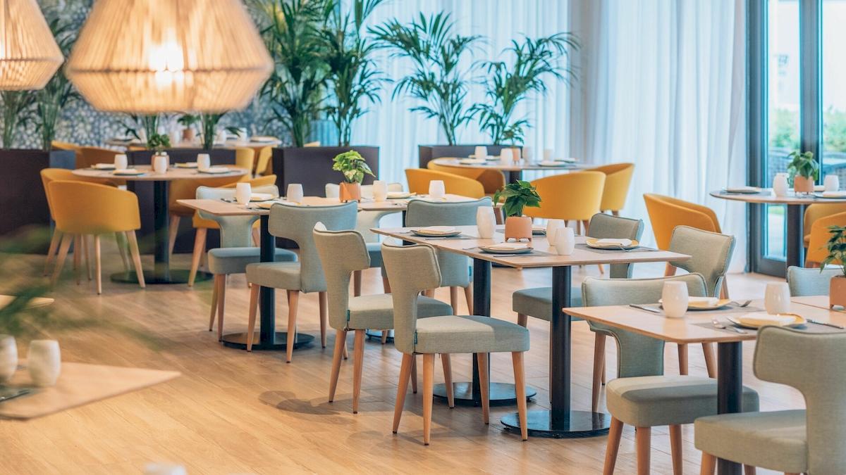 Restaurant des Iberostar Playa de Muro Hotels mit gedeckten Tischen und Stühlen.