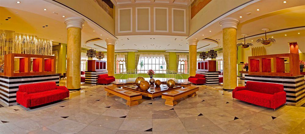Lobby des Iberostar Selection Rose Hall Suites Hotels mit roten Sesseln und goldenen Tischen.